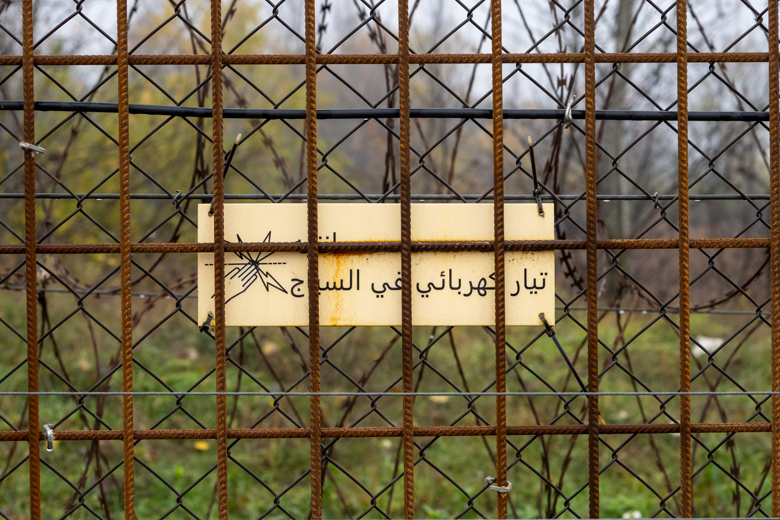 Warning sign about electric shocks in Arabic on the Hungarian-Serbian border fence