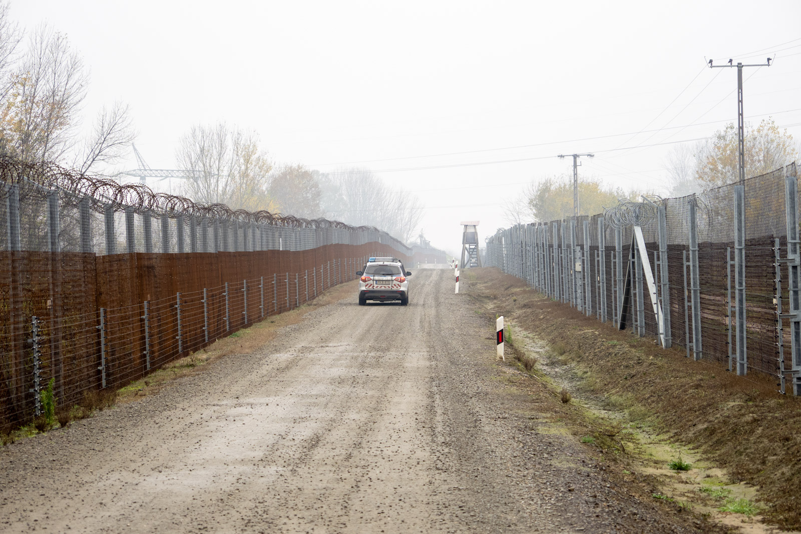 A Hungarian police car patrolling between the parallel border fences